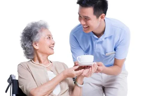 Male nursing worker serving tea to senior woman 写真素材
