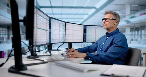 Male Office Manager Analyzing Multiple Business Monitors In Medical Office. Stock Photos