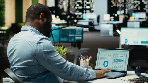 Male office worker fact checking numbers and finance data metrics at night Stock Photos