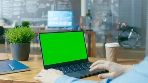 Male Office Worker at His Desk Works on a Laptop with Mock-up Green Screen.  Stock Footage
