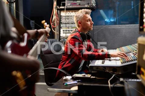 Male operator adjusting sounds while recording music in studio Stock Photos