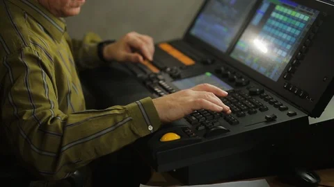 The male operator, the illuminator at the remote control, programs the stage Stock Footage 126980486