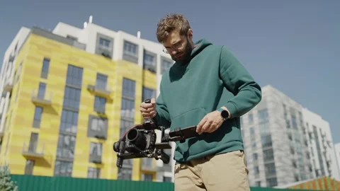 Male operator with stabilizer for camera in his hands shoots video against Video stock 244268482
