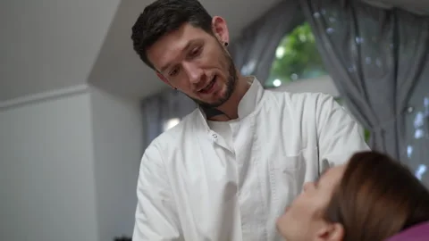 Male osteopath performing neck manipulation on a female patient Stock Footage 333506913