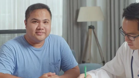 Male Patient Smiling To Camera While A Doctor Writing Prescription Stock Footage 249608468