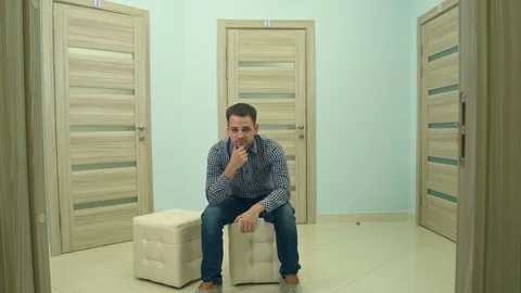 Male patient waiting for doctor's appointment nodding his head and looking into Stock Footage