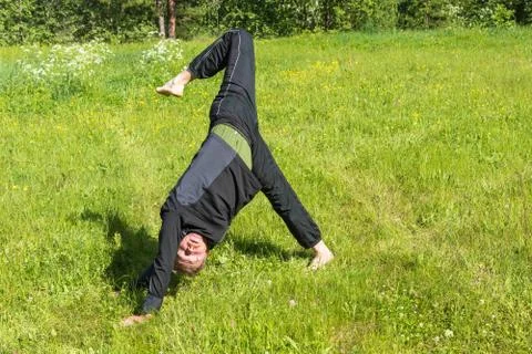 Male performs asanas on the grass. Stock Photos
