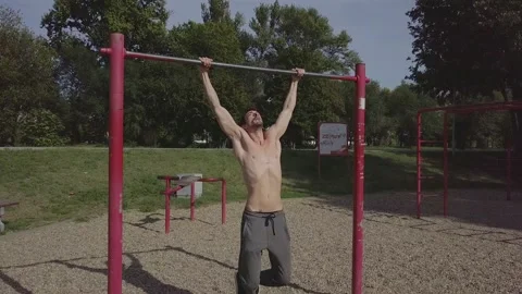 Male person doing pull ups on the bar in the park. Male athlete performing Stock Footage 141479274