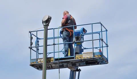 Male person working on an elevator platform, electrical lighting connection Stock Photos