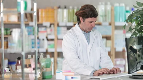 Male pharmacist working at computer in pharmacy Stock Footage 343710013
