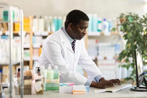 Male pharmacist working at computer in pharmacy Stock Photos