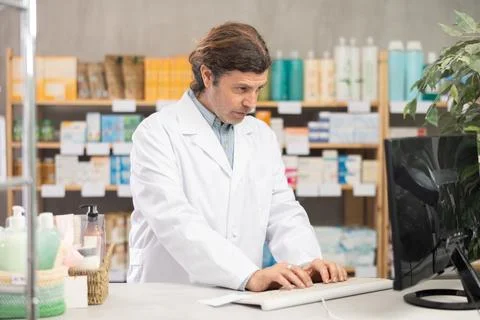 Male pharmacist working at computer in pharmacy Stock Photos
