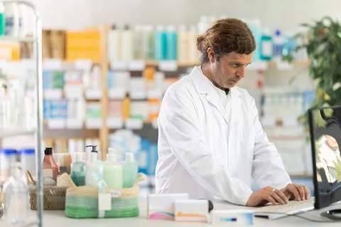 Male pharmacist working at computer in pharmacy Stockfoto's