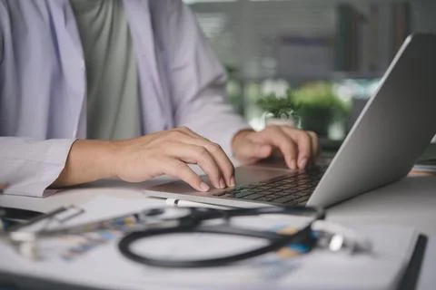 Male physician using computer for online patient consultation, managing dig.. Stock Photos