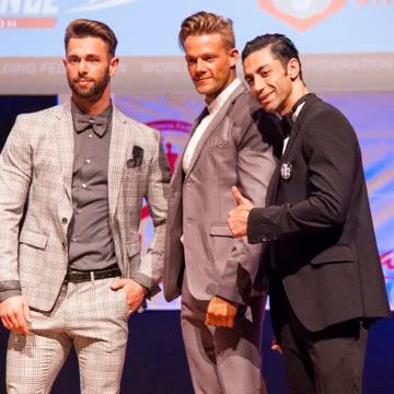 Male physique models show their best in suit on stage Stock Photos