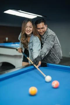 Male pool player teaching the female player to poke the white ball Stock Photos