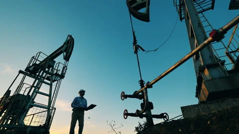 Male power worker is observing a functioning pumpjack Stock Footage 142428493