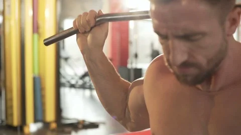 Male practicing rear pull-downs in gym and finishing exercise, his face strained 動画素材 75559622