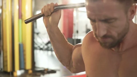 Male practicing rear pull-downs in gym and finishing exercise, his face strained 動画素材 75565047