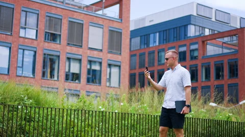 Male professional reading message on mobile phone against modern architecture Stock Footage 345828909