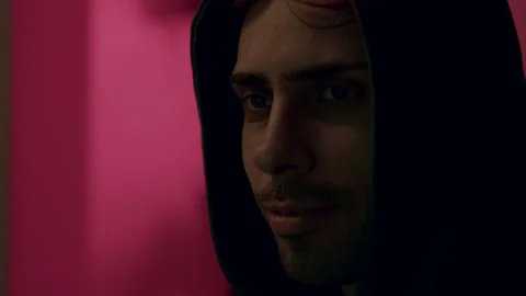 Male programmer in a dark hoodie, focused on coding session, with vibrant pink Stock Footage 323322322