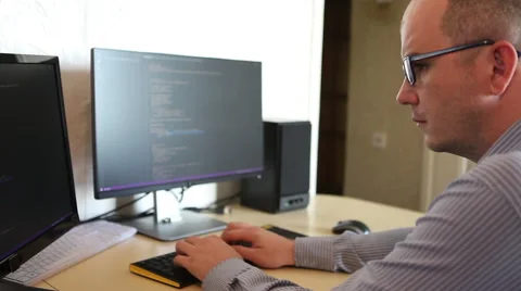 Male programmer fixes the code sitting at the computer. side view Stock Footage 64830781