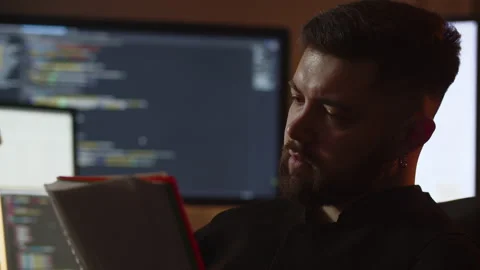 A male programmer makes entries in his notebook. A creative young programmer Stock Footage 236564176