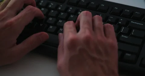 Male programmer sitting behind a computer and typing code on a keyboard. Video stock 284382237
