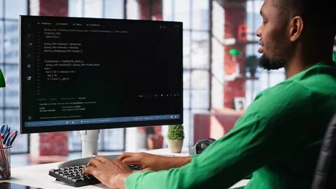 Male programmer types code on computer and running script Stock Photos