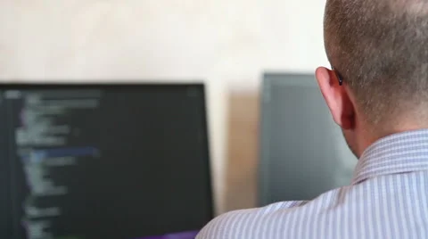 Male programmer is typing the code sitting at the computer. back view Stock Footage 64830883