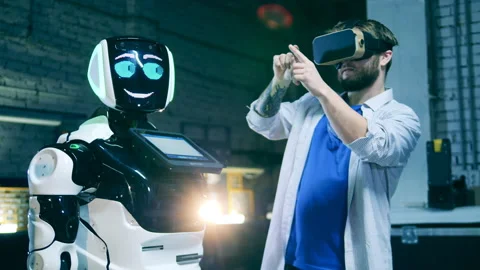 Male programmer in VR-glasses is communicating to a robot Stock Footage 149040761