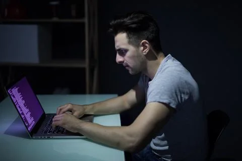 Male programmer working on desktop computer at white desk in office in dark 写真素材