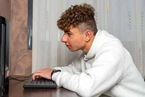 Male programmer working on a desktop computer in the dining room of his house Stock Photos