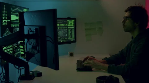 Male programmer working intently at a modern workstation with multiple screens Stock Footage 313931075