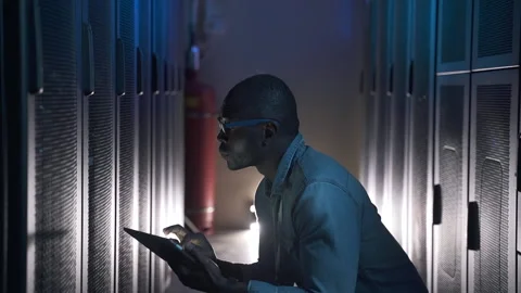 Male programmer working with tablet and inspecting server shelves, sitting in Stock Footage 161744798