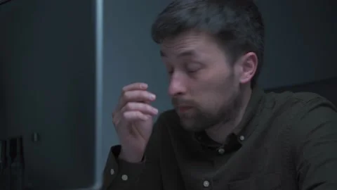 A male programmer works late at the computer in the office, rubbing his eyes Stock Footage 217999584