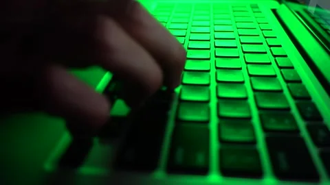 A male programmer writing code on a keyboard. Green lighting. close-up Stock Footage 276488412