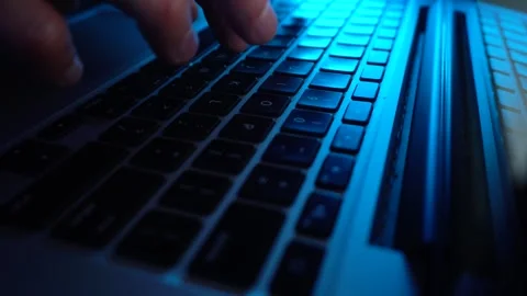 A male programmer writing code on a keyboard. Blue lighting Stock Footage 277360765