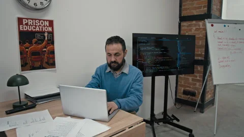 Male Programming Teacher Sitting at Desk in Prison Classroom during Lesson Stock Footage 314054096