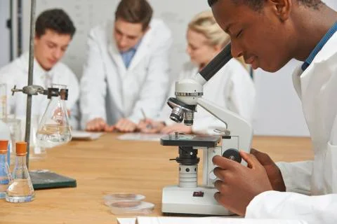 Male Pupil Using Microscope In Science Class Stock Photos