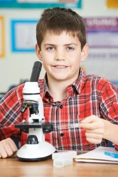 Male Pupil Using Microscope In Science Lesson Stock Photos