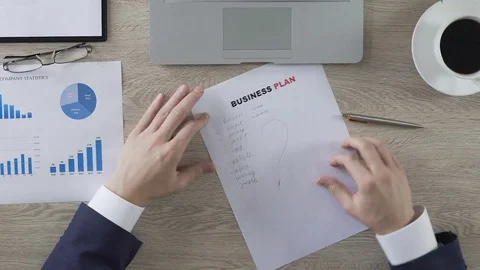 Male putting question mark next to business plan elements, balling paper, doubts Stock Footage 76760991
