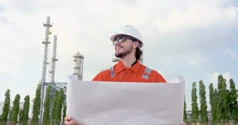 Male refinery engineer smiles over blueprint in slow motion near processing Stock Footage 337392454
