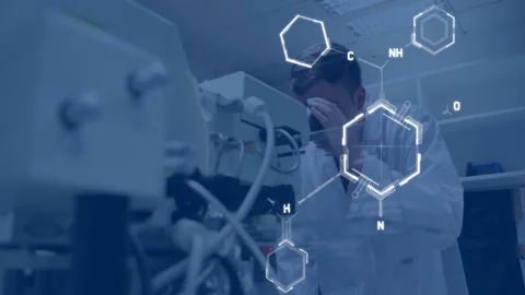 Male researcher leaning into microscope adjusting knob causing hexagon HUD Stockbeeldmateriaal 331272470