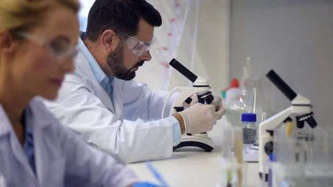 Male researcher looking through microscope in lab Stock Footage 80357513