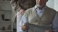 Male retiree reading newspaper, female hugging from behind, loving tenderness 4k or 4k+ Resolution