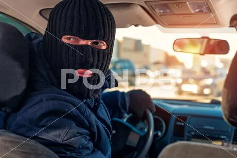 Male robber in black mask driving a stolen car Stock Photos