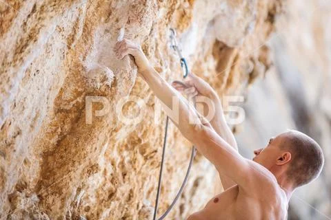 Male rock climber clipping rope Stock Photos