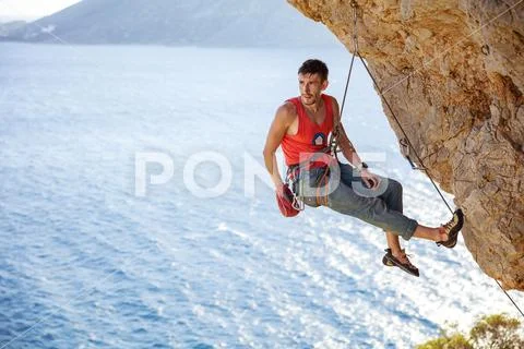 Male rock climber resting while hanging on rope Stock Photos