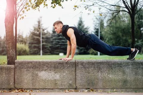 Male runner doing exercise, workout in the fall park. Push ups with bench Stock Photos